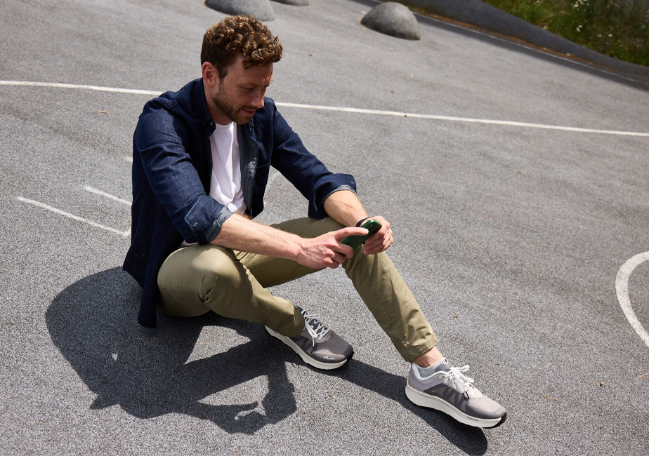 Läufer trägt den Joe Nimble Addict Pro-R Laufschuh in Grau in seiner Freizeit und sitzt auf dem Asphalt