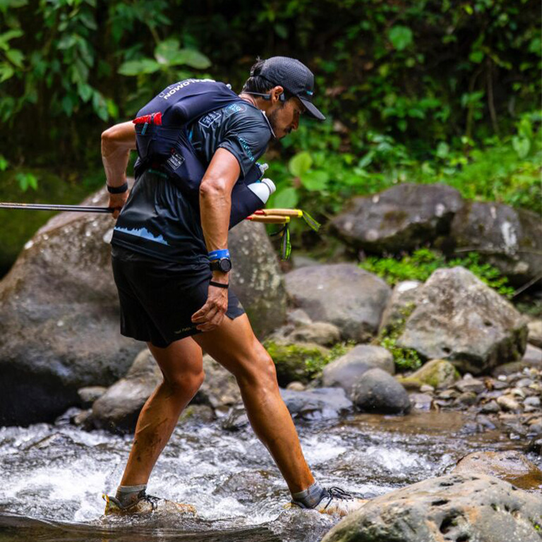 Läufer beim Marathon im Regenwald der durch Bäche läuft
