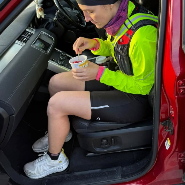 Reka sitzt in Sportklamotten im Auto und isst