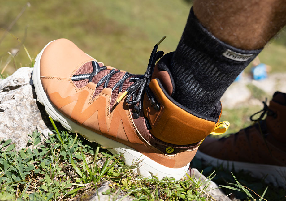 Der Joe Nimble Mountain Addict Wanderschuh in braun angelehnt an einen Stein