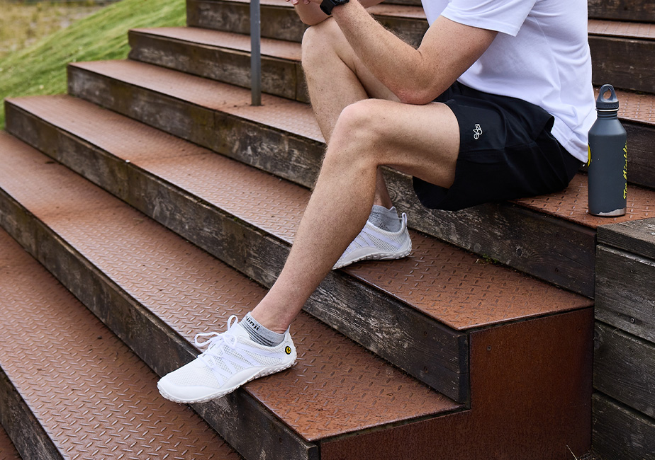Mann sitzt auf einer Treppe mit dem Joe Nimble nimbleToes Gymschuh in weiß