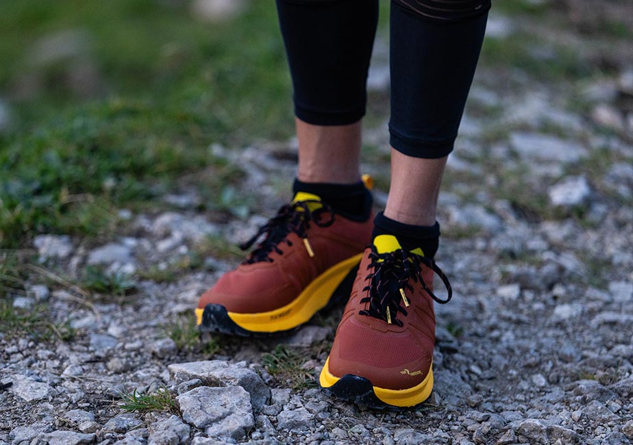 Der Joe Nimble Trail Addict Pro-R Traillaufschuh in Braun auf einem Geländeweg