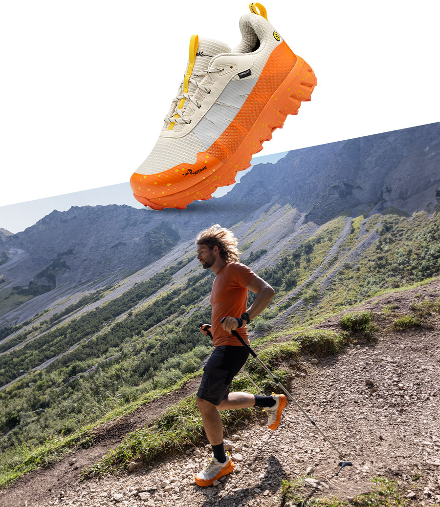 Closeup des Joe Nimble Explore Addict Trailschuhs in Orange mit Läufer in den Bergen